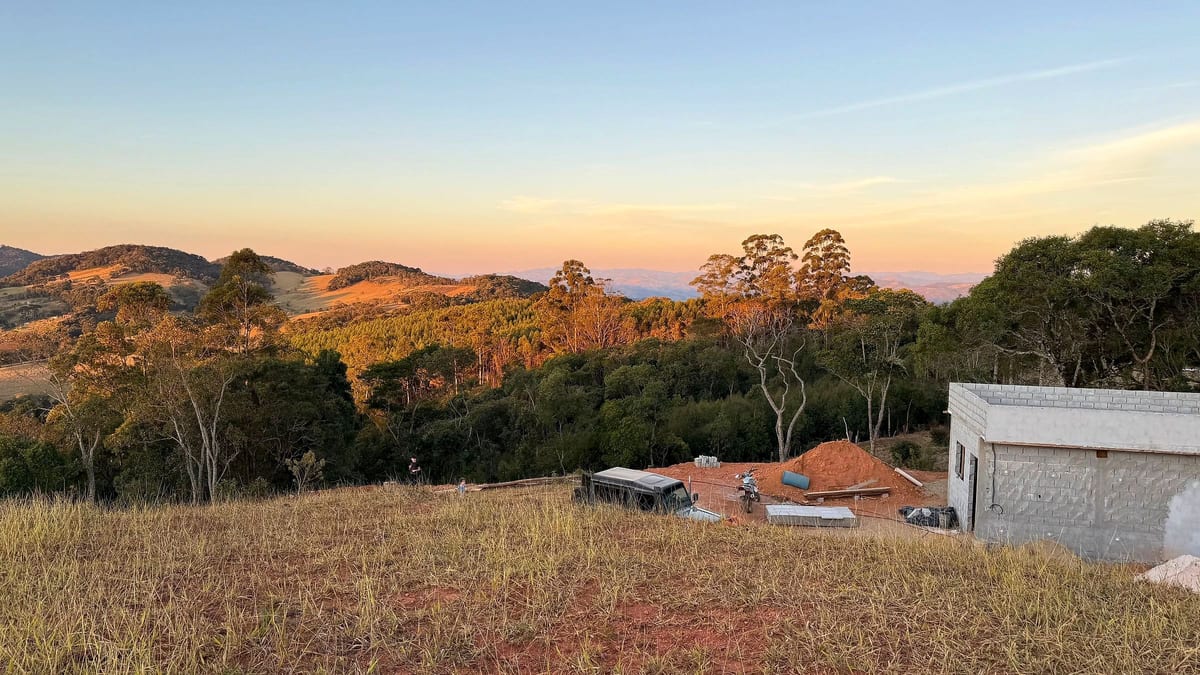 Entardecer sobre o Alto das Pitangueiras, com a casa construída à direita e as montanhas ao fundo